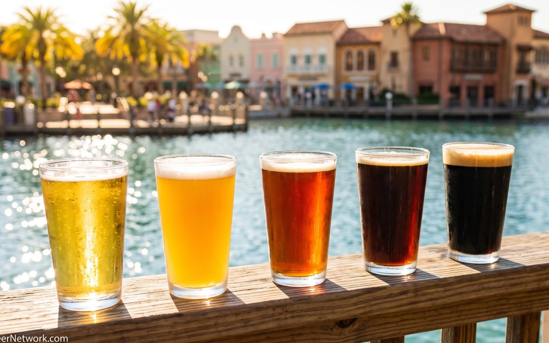 Row of five beers from pale lager to stout on a ledge beside a lagoon