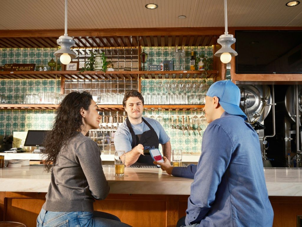 Bartender serving two customers at a brewery taproom bar